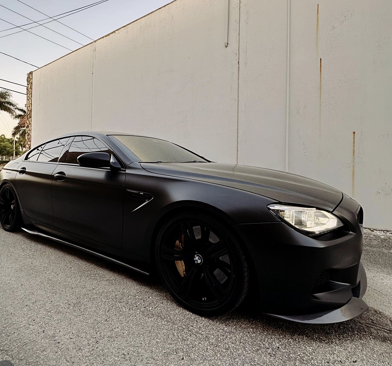 BMW M6 Gran Coupé wrapped in matte black vinyl with black wheels and gold brake calipers